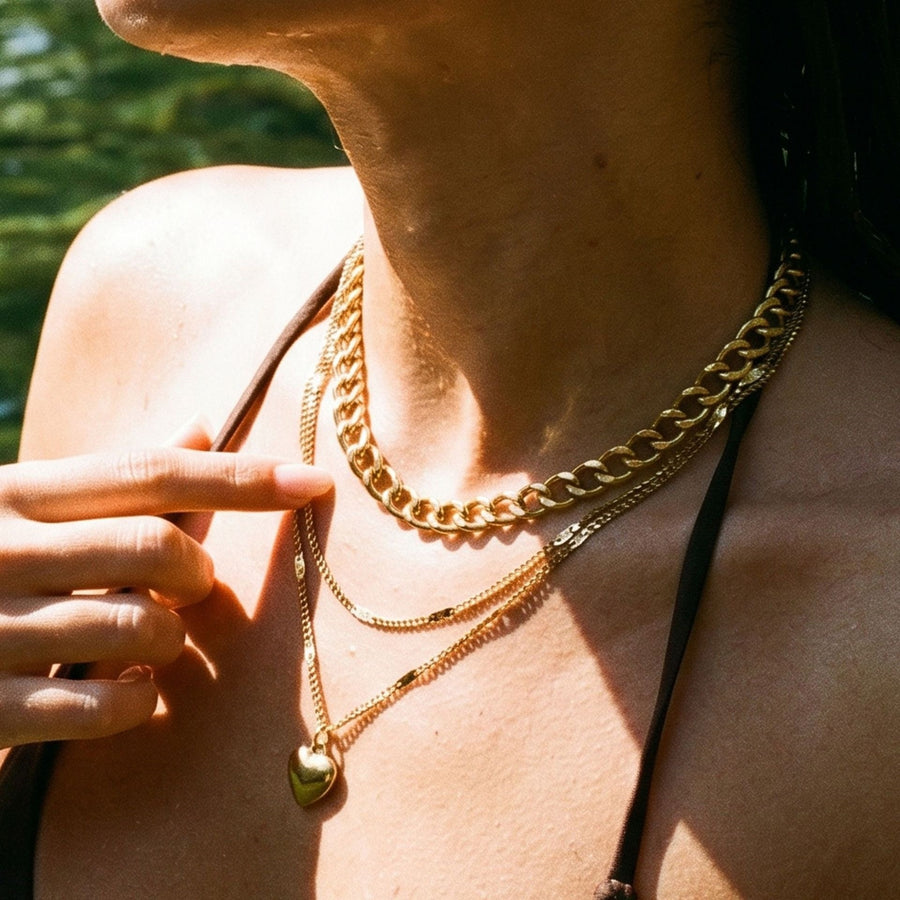 Gold layered chains on a sunlit collarbone